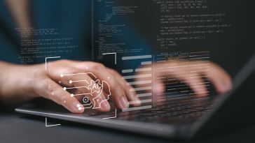 A close up of hands typing on a laptop with holographic images of code and AI icons floating in the foreground.