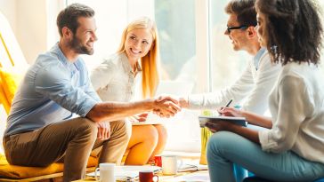 Two people shaking hands in group during interview
