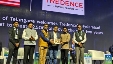 Tredence executives stand onstage at an event.