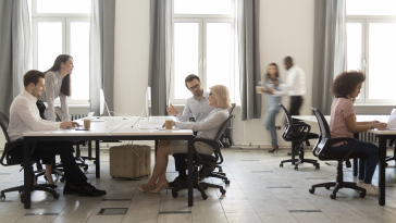 Coworkers sitting at workspaces in large office