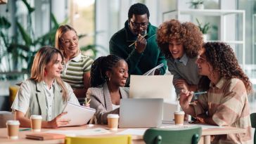 Several team members review ideas for an ongoing project while working together in an office