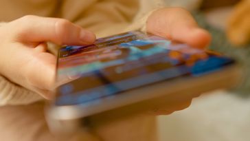 A close up of hands on a smartphone scrolling through online content.