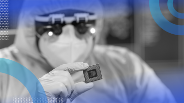 A researcher in a clean suit holds a semiconductor