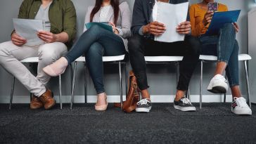 Image of four people sitting in chairs holding resumes