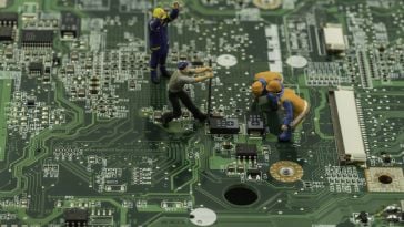 Miniature figures work on a motherboard to show the idea of product teams building a piece of technology.