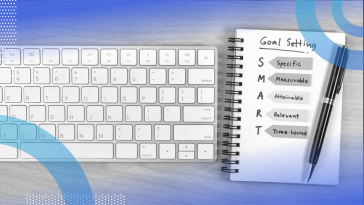 A notepad with a definition of "SMART goals" next to a keyboard
