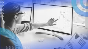 A financial analyst looks at dashboards on computer screens