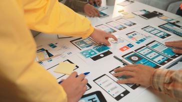 A team looks over wireframe printouts.