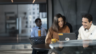Two team members chat around a laptop in an office