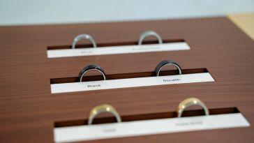 Three pairs of Oura Rings are lined up on a wood table. 