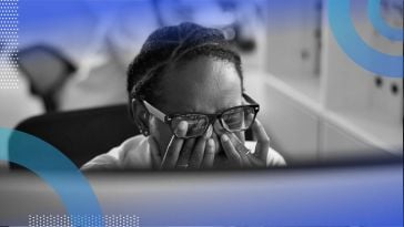 A developer rubs their eyes while looking at a computer screen