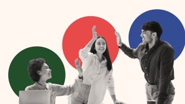 A photo of three employees high-fiving in front of colorful shapes to show the idea of working on a team that puts people first and has great employee engagement. 