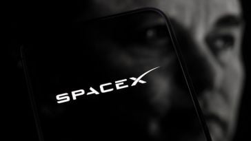 The SpaceX logo superpositioned over the face of CEO Elon Musk.