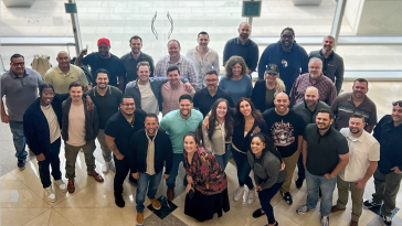 Beyond Finance employees pose for a large group photo in a building lobby.
