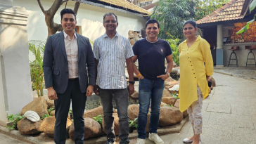 Sakthivel Muniraju poses for a photo with three other team members in an outdoor space in Bangalore