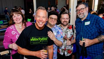 Five VelocityEHS team members pose for a group photo during a company event. 