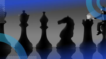 A series of chess pieces with someone sitting on the pawn working on a laptop