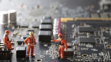 A photo of miniature construction figures working on a motherboard to show the idea of teams building software. 