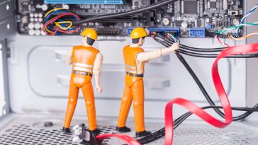 MIni figures working on the hardware of a computer to show the idea of working on cyber security. 
