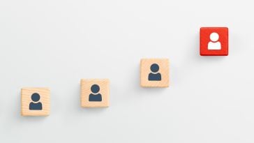 Wooden blocks with icons of people in an ascending pattern with a red one at the top to show the idea of upward career growth. 