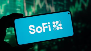 A hand holds up a smartphone with the SoFi logo displayed on the screen.