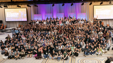 Huntress employees pose for a large group photo in a conference room during a company event.