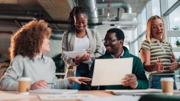 Four employees collaborating on a project together in an office.