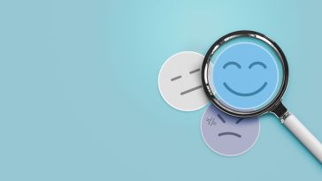 An image of a happy face in a magnifying glass in front of sad faces to show the idea of happy employees who are working on sustainably paced teams. 