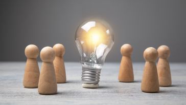 A photo of wooden figures around a lightbulb to show the idea of a great employee experience 