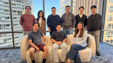 Airwallex teammates sitting and standing in a glass office building.