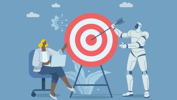 A woman, seated with a laptop on her lap, points toward a large bullseye target while a white robot places an arrow in the center of the target. 