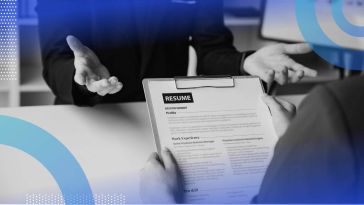 A person hands a resume across a desk on a clipboard