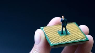 A photo of a miniature figure standing on a microchip to show the idea of working on product teams. 