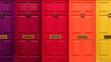 A row of brightly colored doors with door knockers.