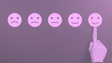 Smiley faces ranging from sad to happy in a row to indicate feedback. A hand picking happy.