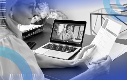 A woman reviews a resume while a man smiles on her laptop display. /remote-recruiting/5-interview-questions-remote-position