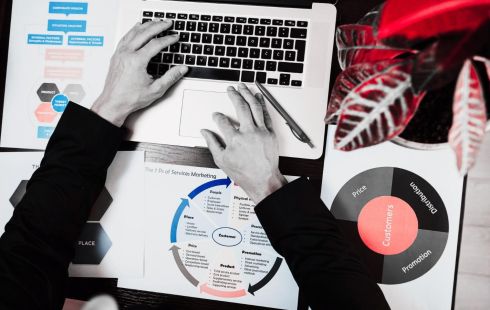 person working at laptop surrounded by marketing materials