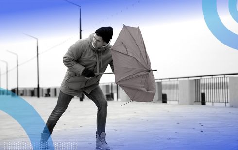 A man battles the wind that is collapsing his umbrella