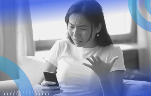 A woman looking angrily at a cell phone. Mercury in retrograde can spark communication snafus, so move carefully to avoid them.