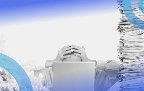 A person covering their head surrounded by files. Data overload is one challenge vertical SaaS companies must overcome.