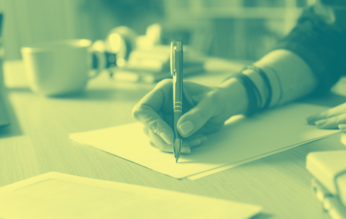A hand holding a pen to an empty page.