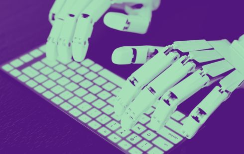 Robotic hands are shown typing on a computer keyboard.