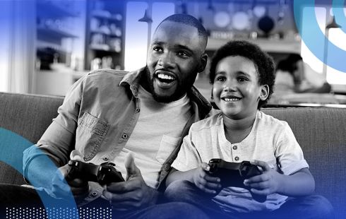A father and son smiling while playing video games together.