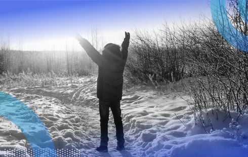 A person standing in the snow welcoming the sun.