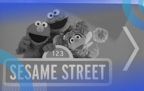 A Sesame Street sign with Elmo, Cookie Monster, and Abbie behind it