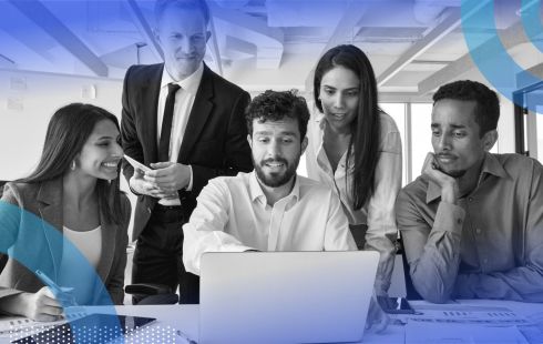 Five coworkers crowded around a laptop looking at the screen with varying levels of interest.