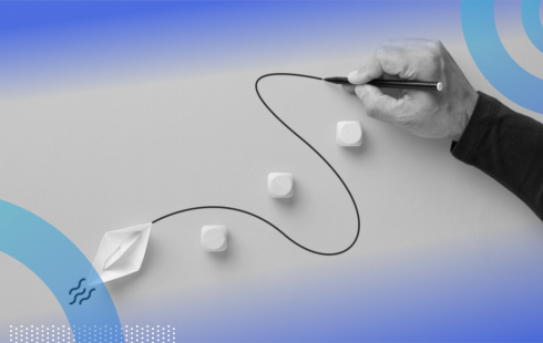A close-up of someone’s hand drawing a curved line for a paper boat to follow around blocks in its path.