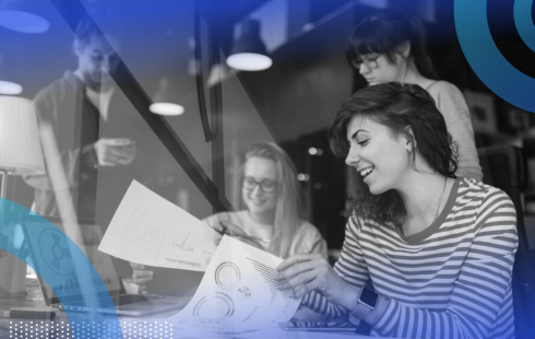 A group of young marketing and PR professionals smiling while looking over paperwork together.