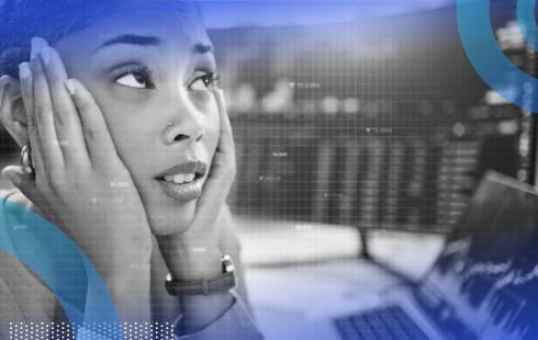 A close-up shot of a stressed tech employee with both hands on either side of her face in front of two monitors with code on them.