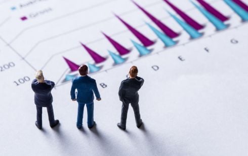 Three miniature figures representing sales leaders stand on a piece of paper with a chart, looking away from the camera.